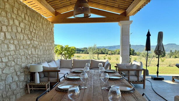 A wooden dining table set for six with plates, glasses, and a woven placemat. - LE Mas Jas, magnificent Mas Provençal - Lauris (Lauris)