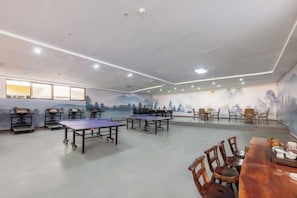 A room with ping pong tables, chairs, and a long table with a vase. - Bingang International Hotel (Xishuangbanna Splash Plaza) (Jinghong)
