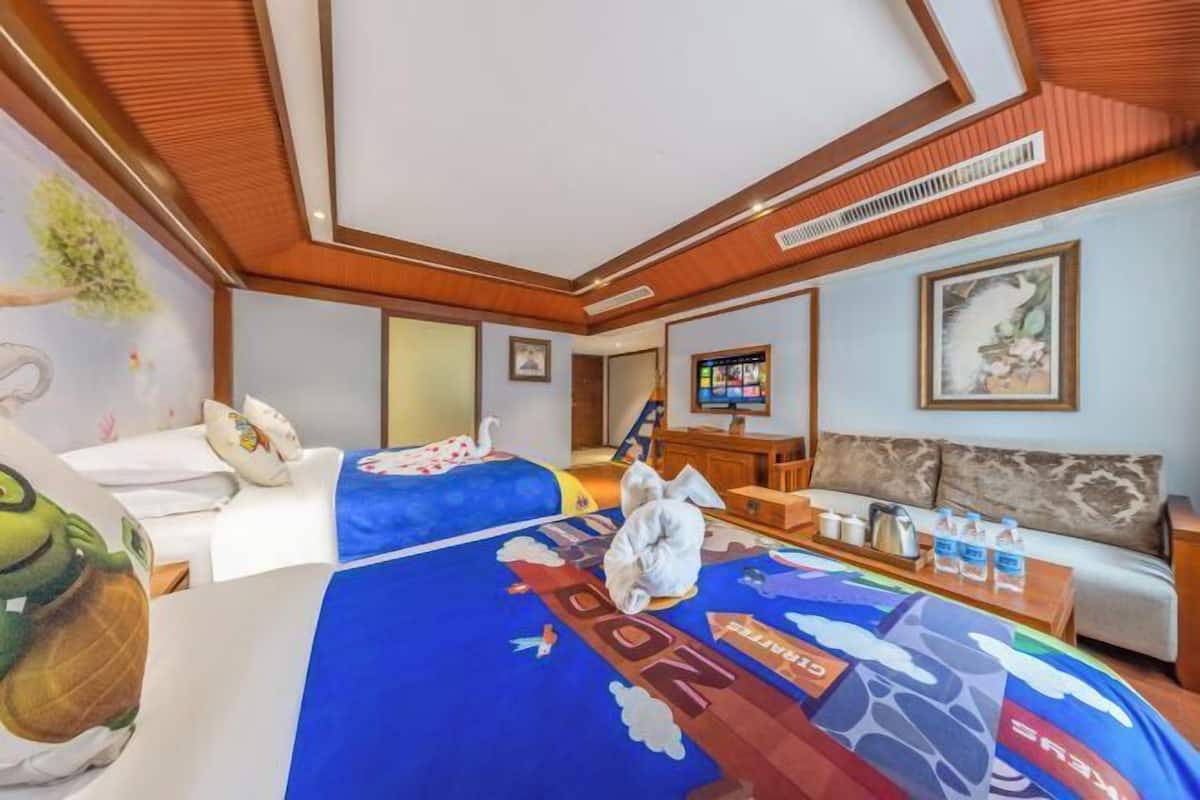 A hotel room with two beds, a sofa, a TV, and a painting on the wall.
