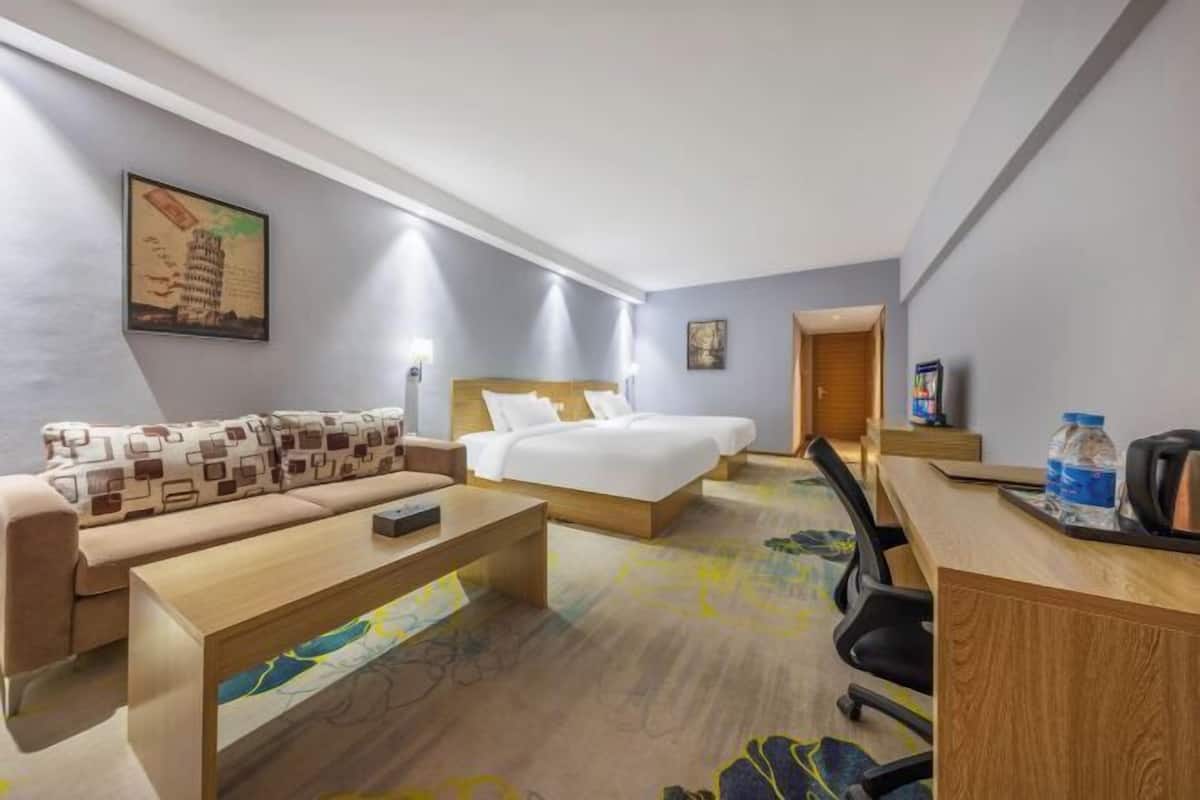 A hotel room with a sofa, a bed, a desk, and a coffee table.