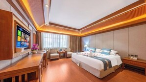 Una habitación de hotel con cama, mesitas de noche, un escritorio y televisor.