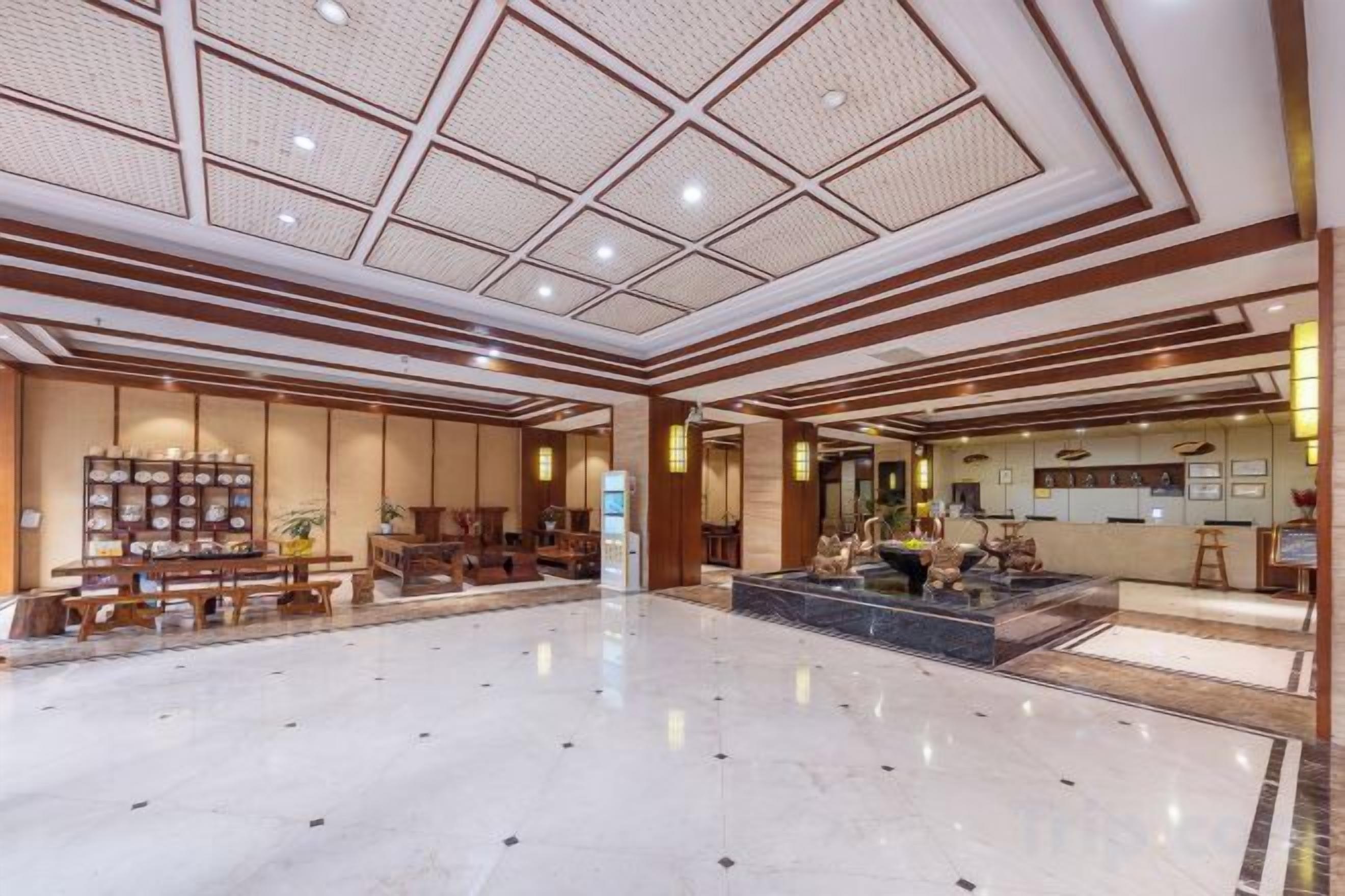 A spacious lobby with a high ceiling, a reception desk, and a seating area.