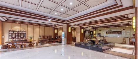 A spacious lobby with a high ceiling, a reception desk, and a seating area.