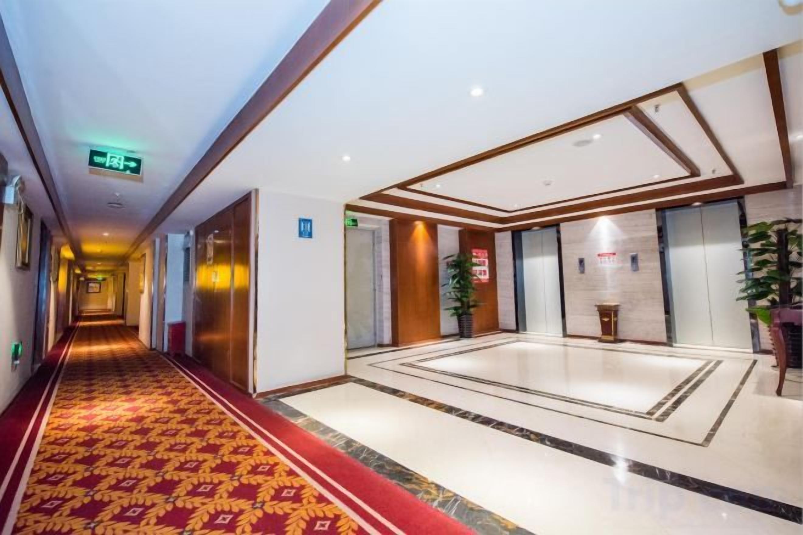 A hotel corridor with a red carpet, a reception area, and a large mirror.