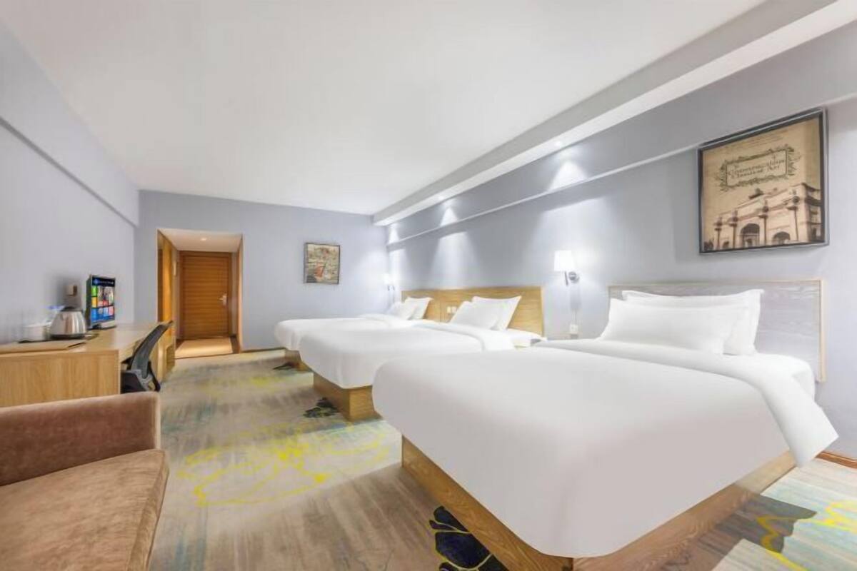 A hotel room with two beds, a desk, a chair, and a framed picture on the wall.