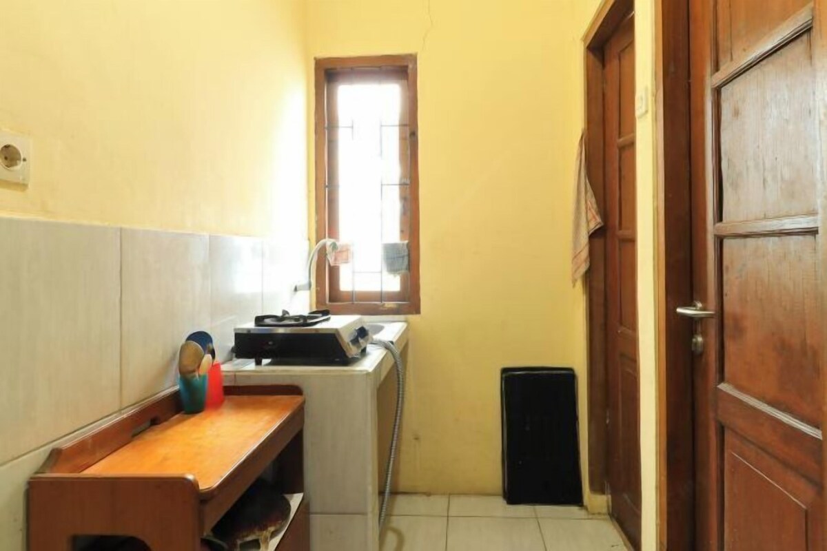 A narrow hallway with a window, a wooden bench, a washing machine, and a door.