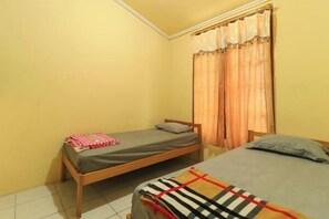 A small room with two single beds, a window with curtains, and a tiled floor. - Villa Kangen Omah (Pacet)