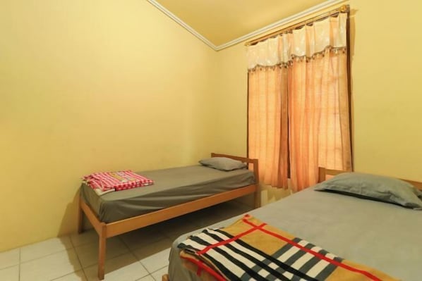 A small room with two single beds, a window with curtains, and a tiled floor. - Villa Kangen Omah (Pacet)