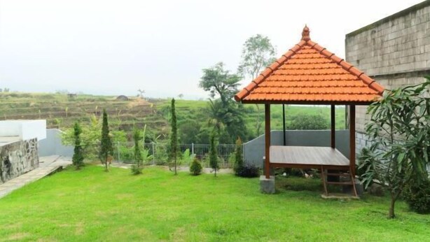 Un mirador con techo de tejas en un área verde, con vistas al campo.