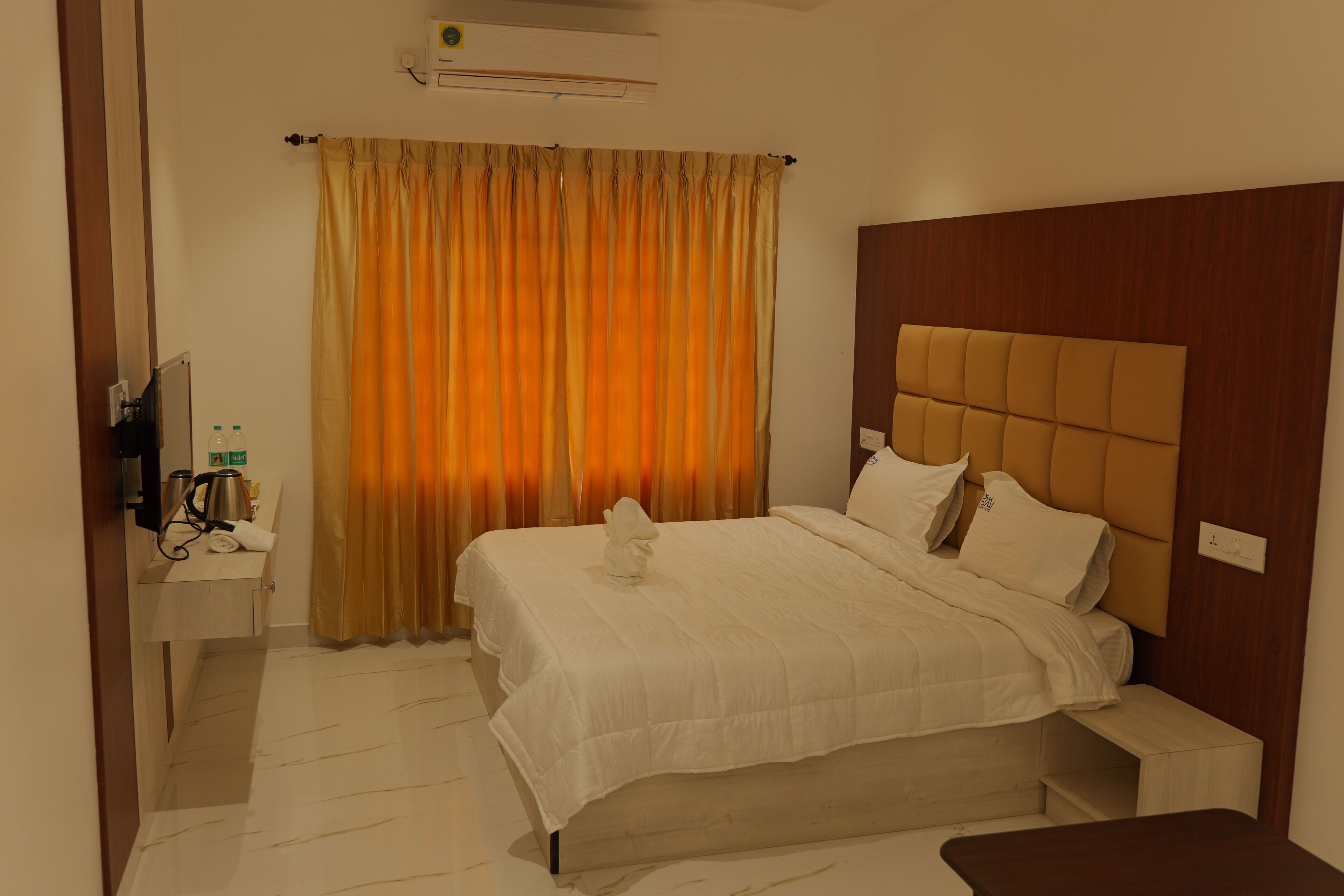 Una habitación de hotel con cama, mesita de noche y televisión.