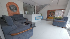 Un salon moderne avec un canapé d’angle, une table basse et un fauteuil bleu.