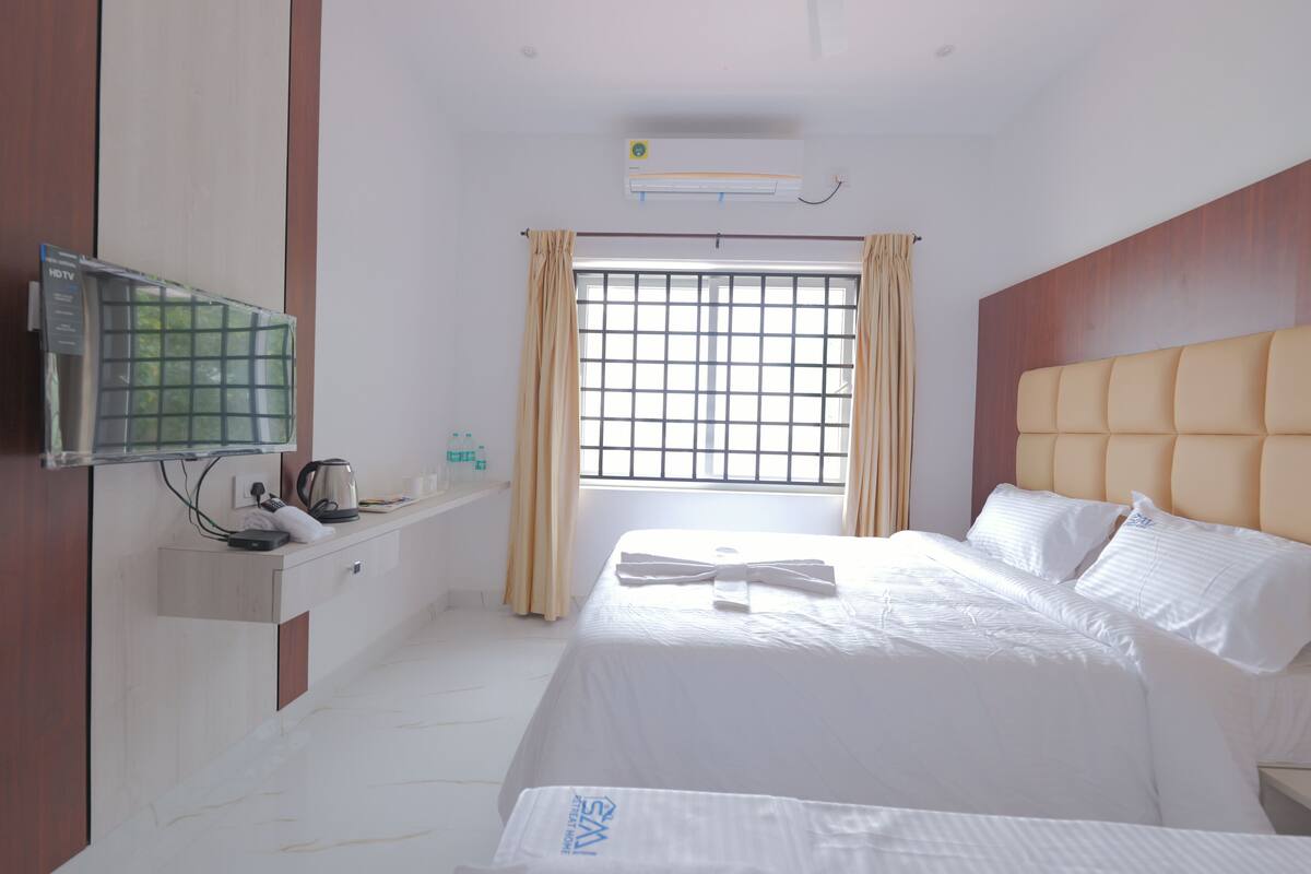 Una habitación de hotel con cama, televisión, ventana con cortinas y aire acondicionado instalado en la pared.