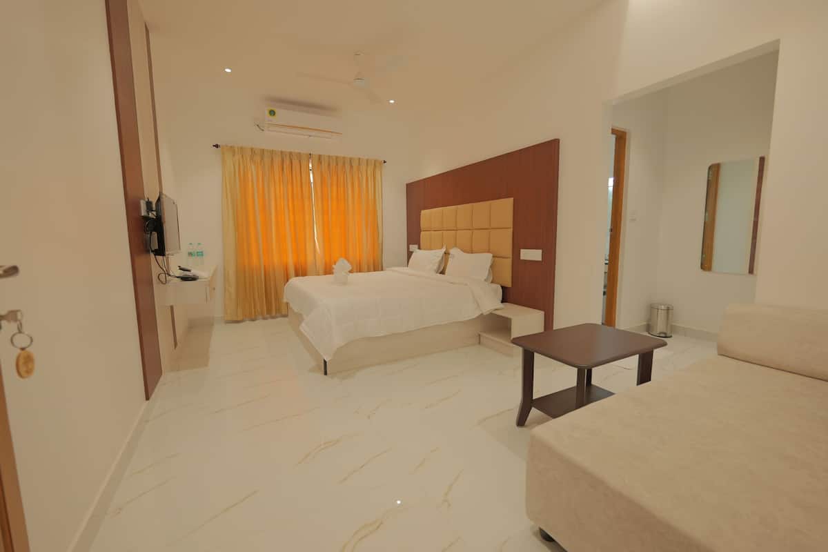 Una habitación de hotel con cama, sofá, una mesita, televisor y baño con espejo.