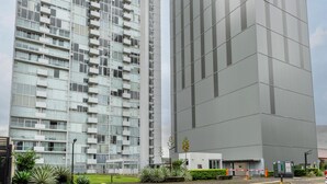 En moderne højhusbygning med glasfacade og flere balkoner.