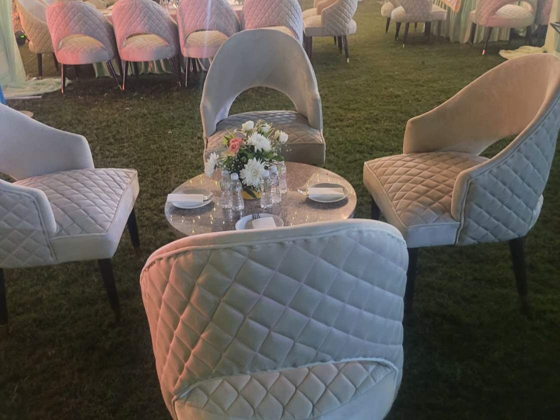 A seating area with cushioned chairs and a round table with a floral centerpiece.