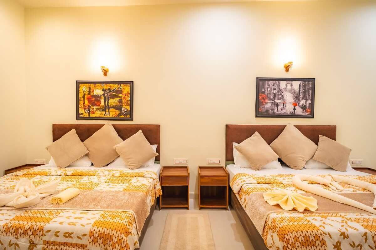 Una camera d'albergo con due letti, ognuno con testiera, due comodini e opere d'arte alle pareti.