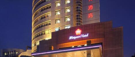 A hotel with a prominent sign, multiple floors, and a well-lit entrance.