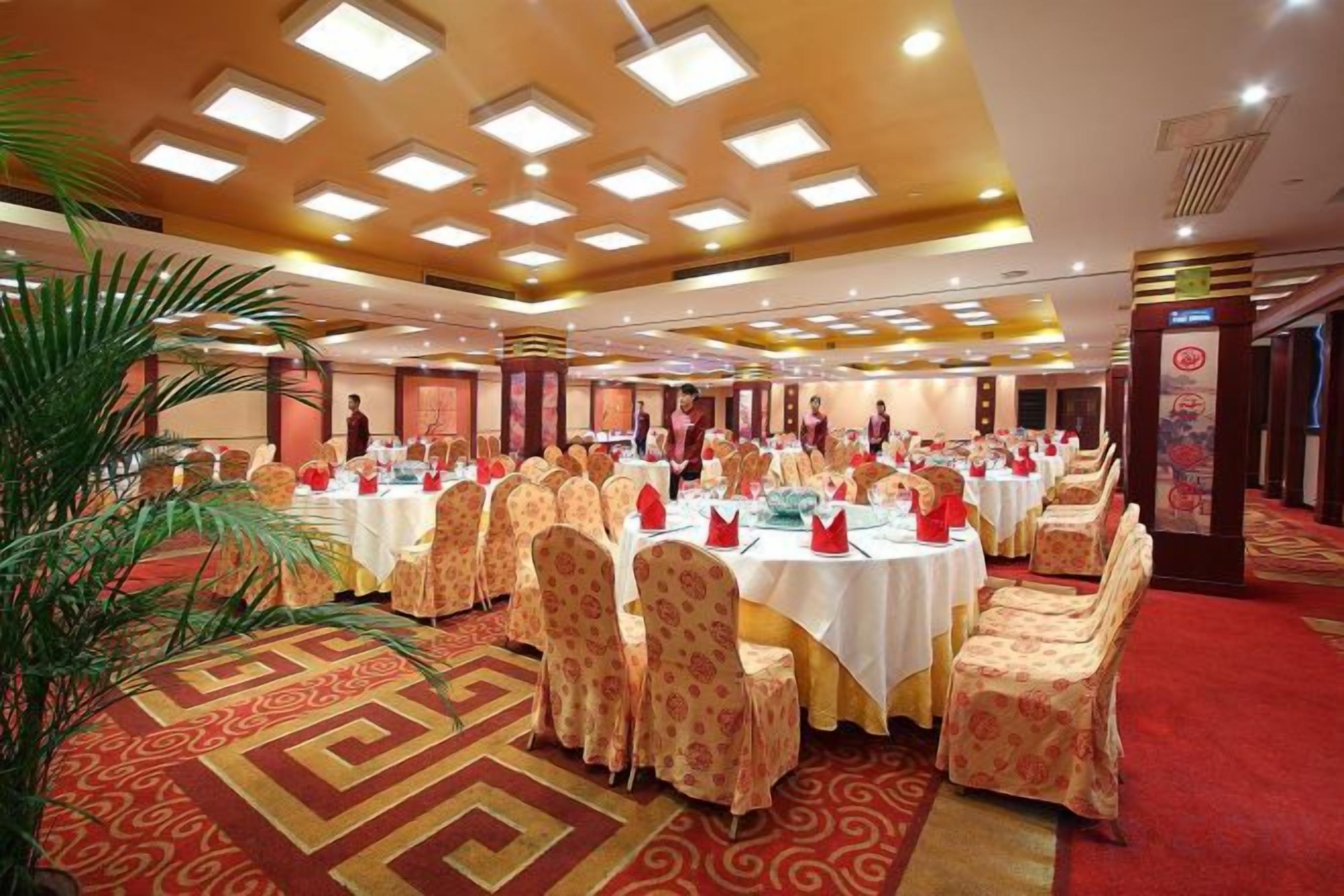 Un salón de banquetes con mesas redondas, sillas y alfombra roja.
