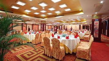 Un salón de banquetes con mesas redondas, sillas y alfombra roja.