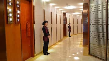 A hotel corridor with wooden doors, a reception area, and a decorative screen.