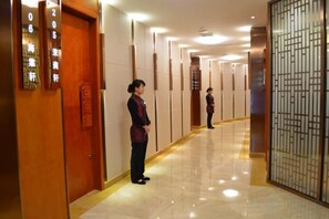 A hotel corridor with wooden doors, a reception area, and a decorative screen. - Meiyuan Hotel (Jiashan)