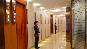 A hotel corridor with wooden doors, numbered signs, and a traditional decorative screen. - Meiyuan Hotel (Jiashan)