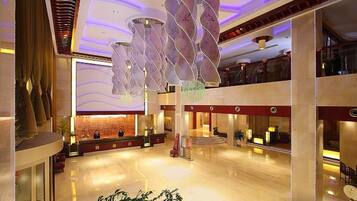 Eine geräumige Lobby mit einer Rezeption, einer großen Pflanze und einer modernen Chandelier.