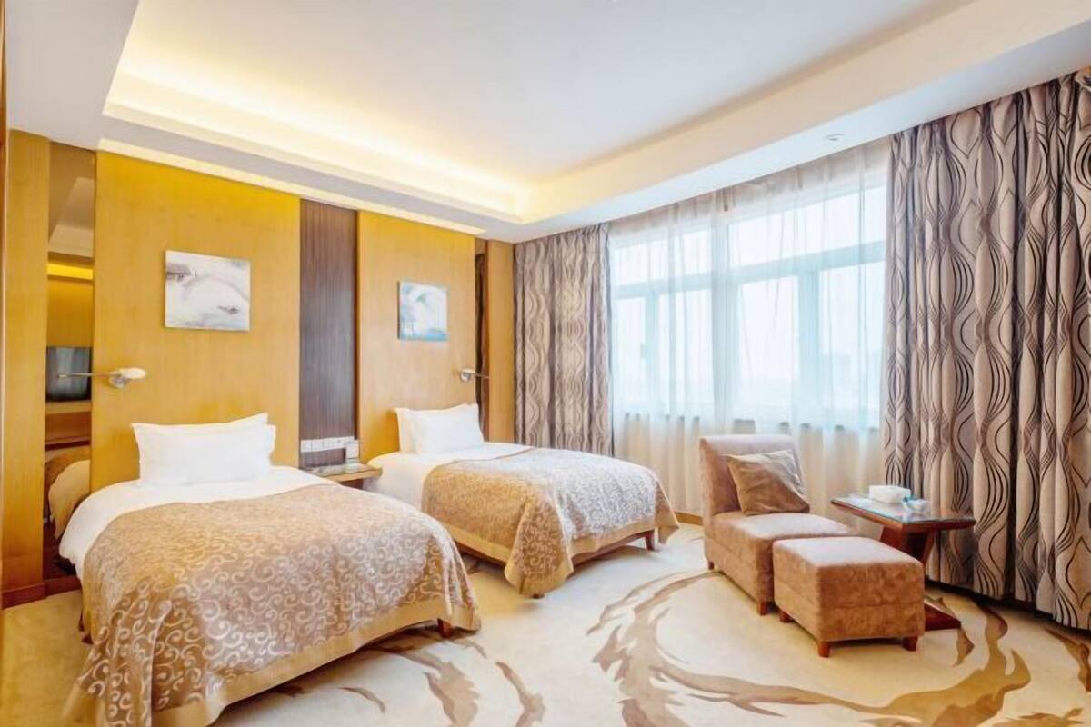 Hotellihuone, jossa on kaksi sänkyä, sohva ja pieni pöytä.