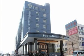 Un hôtel doté d’une façade moderne, d’une entrée imposante et d’une enseigne indiquant qu’il s’agit du Spring Bay Boutique Hotel.