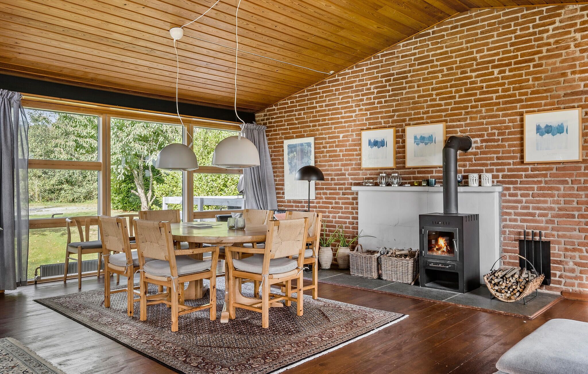 Una habitación acogedora con pared de ladrillo, chimenea y zona de comedor con mobiliario de madera.