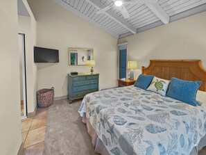 A bedroom with a large bed, a dresser, a television, and a ceiling fan.