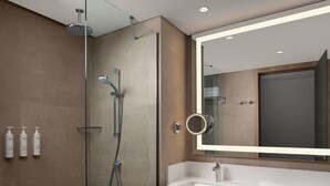 Een moderne badkamer met een douchecabine van glas, een grote spiegel en een wit wastafel.