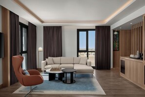 Un salon moderne comprenant un canapé, un fauteuil, une table basse et un téléviseur.