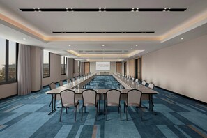 A conference room with a long table, chairs, and a screen at the front. - Courtyard By Marriott Dakar Diamniadio (Diamniadio)