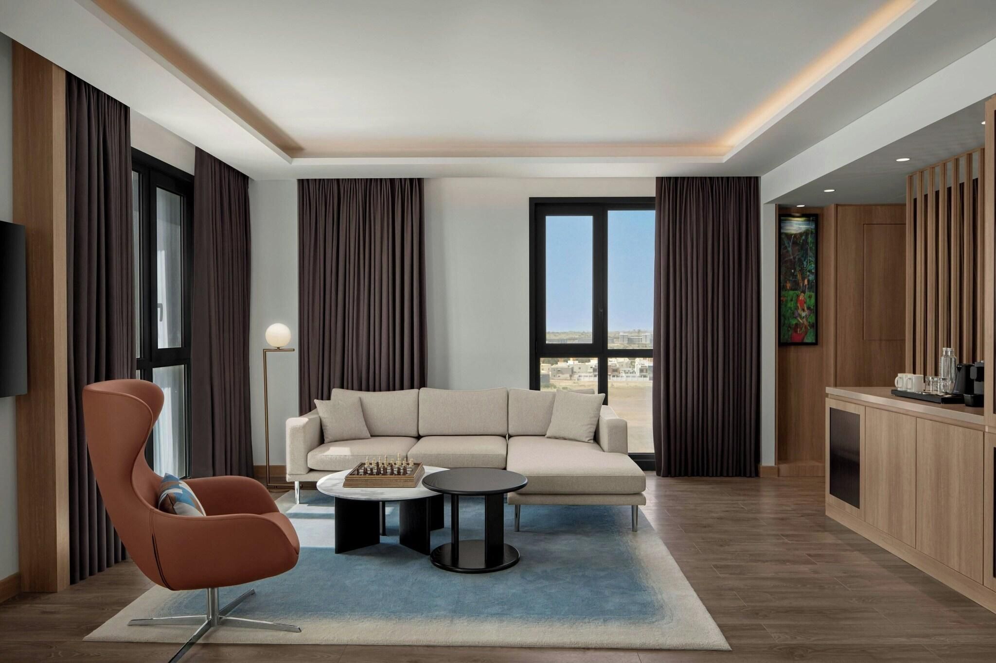 Un salon moderne comprenant un canapé, un fauteuil, une table basse et un téléviseur.