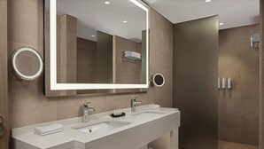 A modern bathroom with a large mirror, two sinks, and a shower area. - Courtyard By Marriott Dakar Diamniadio (Diamniadio)
