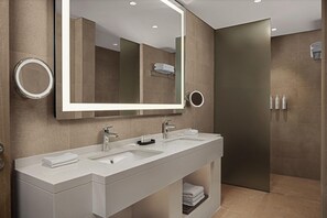 Une salle de bain moderne avec un grand miroir, deux lavabos et un espace douche.