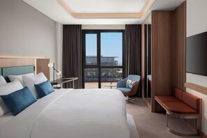 Moderni hotellihuone, jossa on suuri sänky, työpöytä, tuoli ja televisio.