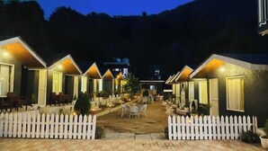 Eine Reihe von Ferienhäusern mit weißem Zaun, jedes mit kleiner Terrasse und Sitzgelegenheit im Freien.