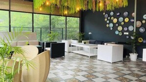 Ein moderner Lounge-Bereich mit Schachbrettmuster-Boden, Korbmöbeln und einer Wand, die mit Keramikplatten dekoriert ist.