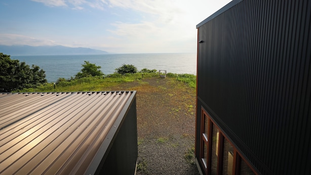 A modern building with a metal roof and a view of the sea.