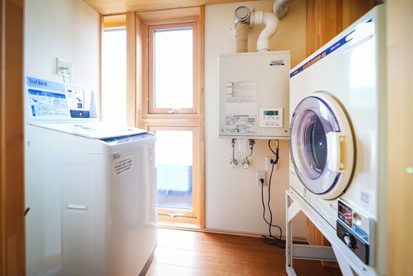 A laundry room with a front-loading washer and dryer, a control panel, and a window. - Hotel Culture Village (Tomari-mura)