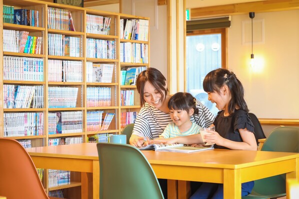 A library with bookshelves filled with books, a wooden table, and chairs.