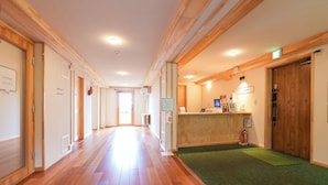 A hotel corridor with wooden floors, a reception desk, and a green carpet.
