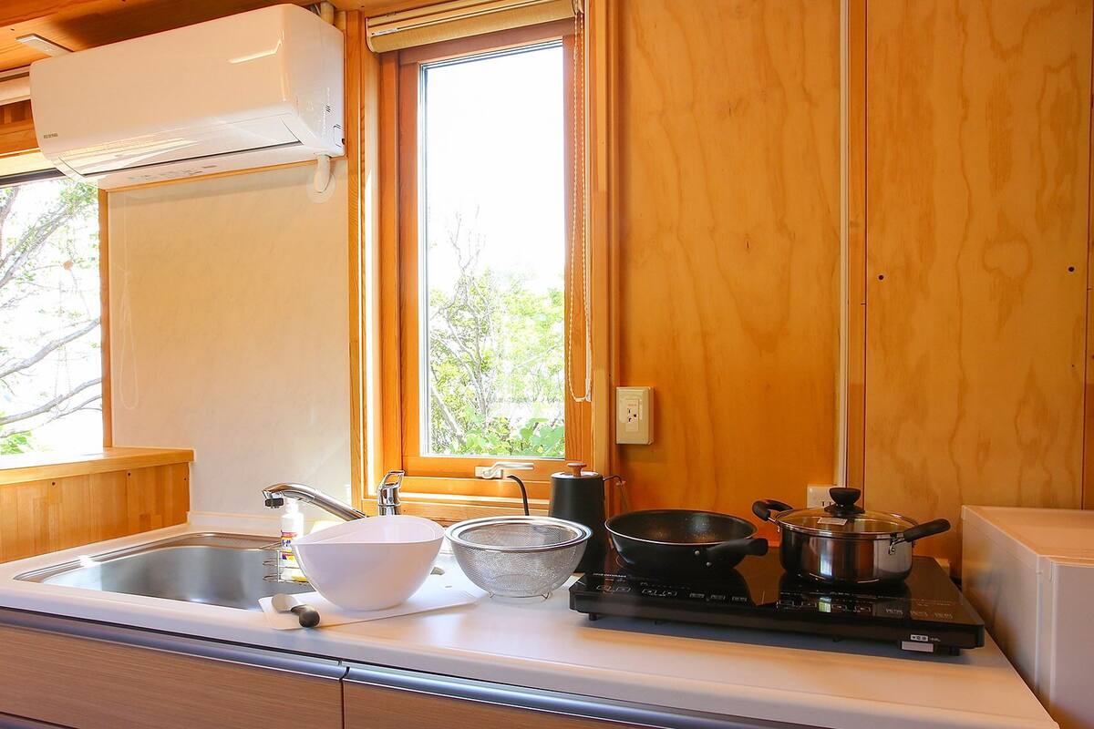 A compact kitchen with a sink, stove, and window.