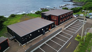 A coastal building with a parking lot, a beach, and rocky cliffs in the background.