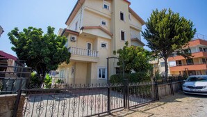 A multi-story residential building with balconies, surrounded by trees and a metal fence. - Avsallar Kepenek Village (Alanya)