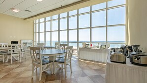 Un espace repas doté de grandes fenêtres, offrant une vue sur la plage, et aménagé avec un buffet.