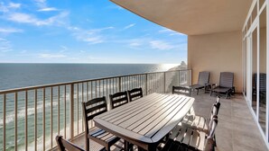 Un balcon avec une table et des chaises, donnant sur l’océan.