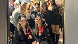 A group of people in a hotel elevator, some wearing costumes.